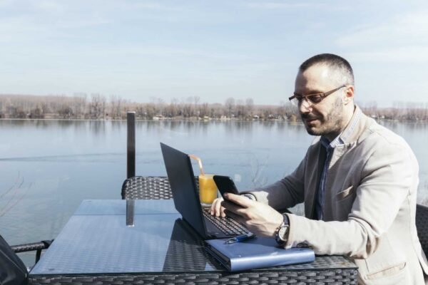 A 2025 Guide to Choosing Between Optimum and Xfinity Wi-Fi Plans businessman-using-smartphone-laptop-near-water-scaled
